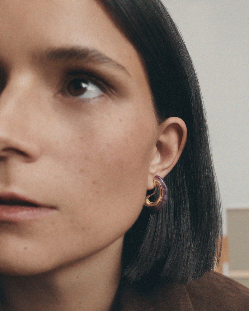 Gold-plated sculptural hoop earrings embellished with a wavy drop purple gemstone