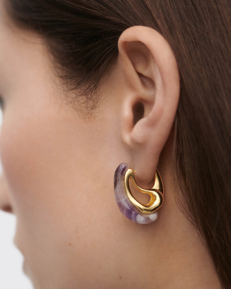 Gold-plated sculptural hoop earrings embellished with a wavy drop purple gemstone